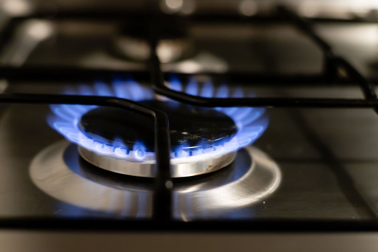 The blue flames of a gas hob burning evenly on a black hob top